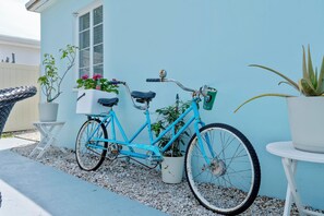 A blue bicycle parked on a gravel path next to a building with a white door and windows. - 2 Bedroom in WPB - Spacious Backyard - Prime Location (Unknown)
