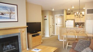 A living room with a fireplace, television, and a dining area with chairs and a table. - Stratton Mountain Resort (Stratton)