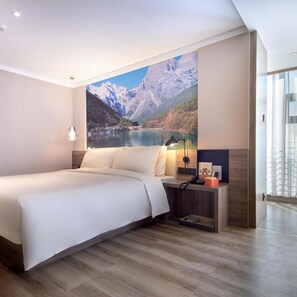 A modern bedroom with a large bed, a nightstand with a lamp, and a wall-mounted phone. - Atour Hotel Kunming South High Speed Railway Station University Town (Kunming)