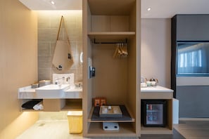 A modern bathroom with a built-in shower, a vanity with a mirror, and a small refrigerator. - Atour Hotel Nankong Quzhou (Quzhou)