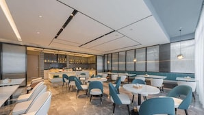 A modern restaurant with a bar area, seating with tables and chairs, and a view through large windows. - Atour Hotel Nankong Quzhou (Quzhou)