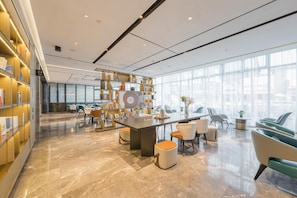 A modern interior with a central bar area, seating, and a large bookshelf. - Atour Hotel Nankong Quzhou (Quzhou)
