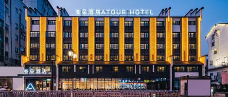 A hotel with a modern facade, multiple floors, and illuminated signage.