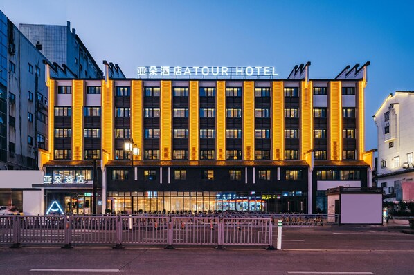 A hotel with a modern facade, multiple floors, and illuminated signage. - Atour Hotel Nankong Quzhou (Quzhou)