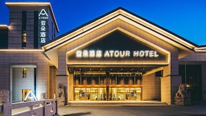 A hotel entrance with a prominent sign, a stone lion statue, and a modern facade. - Atour Hotel (Suzhou)