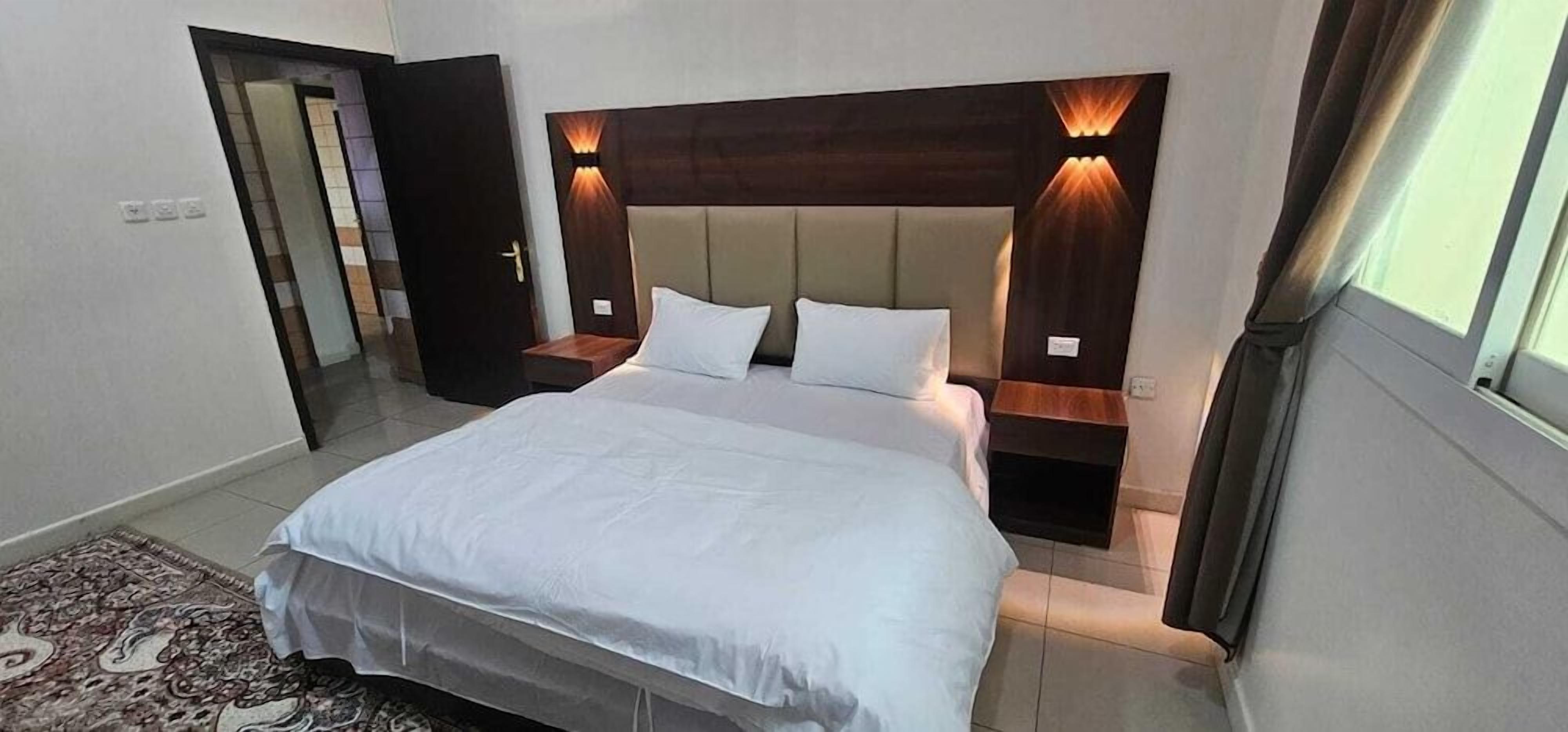 Un dormitorio con una cama grande, dos mesitas de noche e iluminación empotrada.