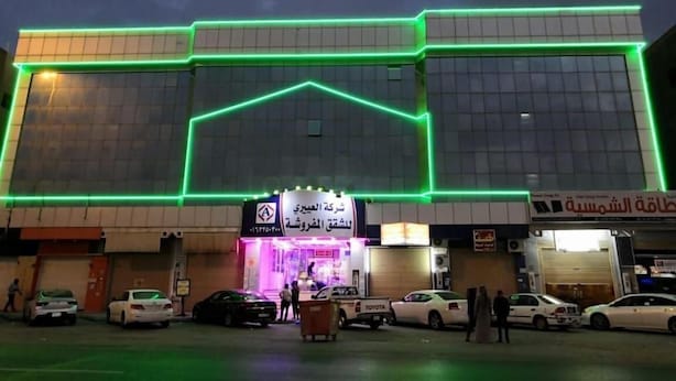A multi-story building with a prominent entrance and a parking lot in front. - Al Eairy Apartments Al Qassim 1 (Buraydah)