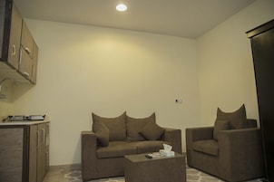 Un espacio habitable pequeño con sofá, mesa de centro y una zona de kitchenette.