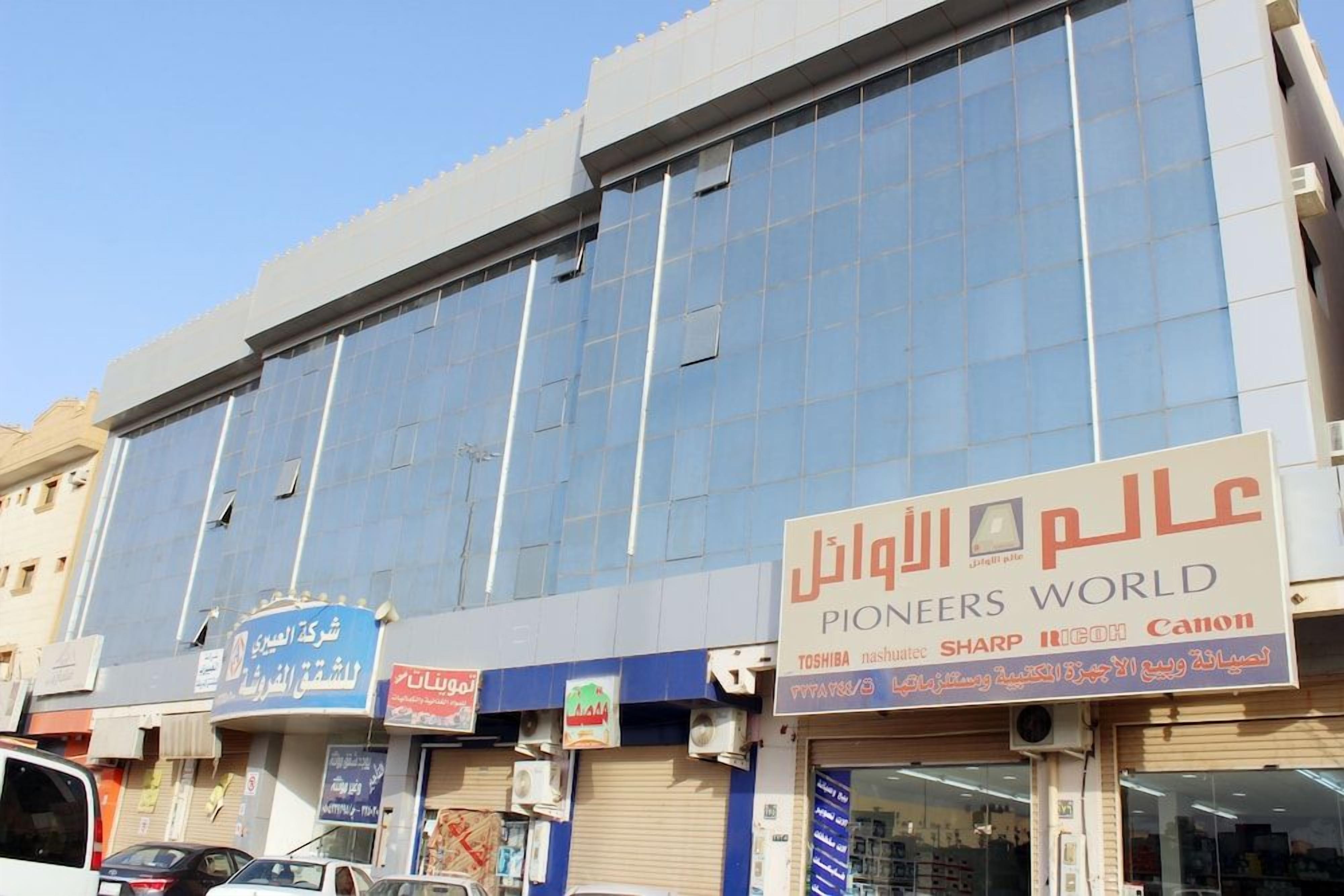 A commercial building with multiple storefronts, including a visible sign for 'Pioneers World' and other businesses.