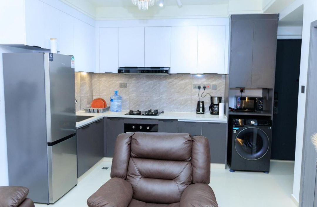 A compact kitchen with a refrigerator, stove, microwave, and washing machine.