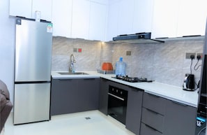 A modern kitchen with a stainless steel refrigerator, a gas stove, and a water dispenser. - Cozy 1-bedroom apartment in charming Nairobi with a city view (Nairobi)