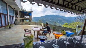 A terrace with a table and chairs, a person seated, and three cocktails on the table. - Mount Himalayan Hotel & Spa Gangtok (Gangtok)