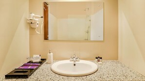 A bathroom with a sink, mirror, hairdryer, and toiletries. - Mount Himalayan Hotel & Spa Gangtok (Gangtok)