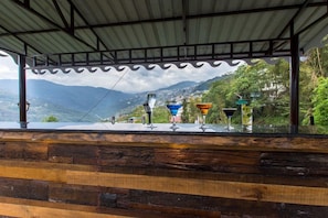 A wooden bar with a view of mountains and a covered area with a metal roof. - Mount Himalayan Hotel & Spa Gangtok (Gangtok)