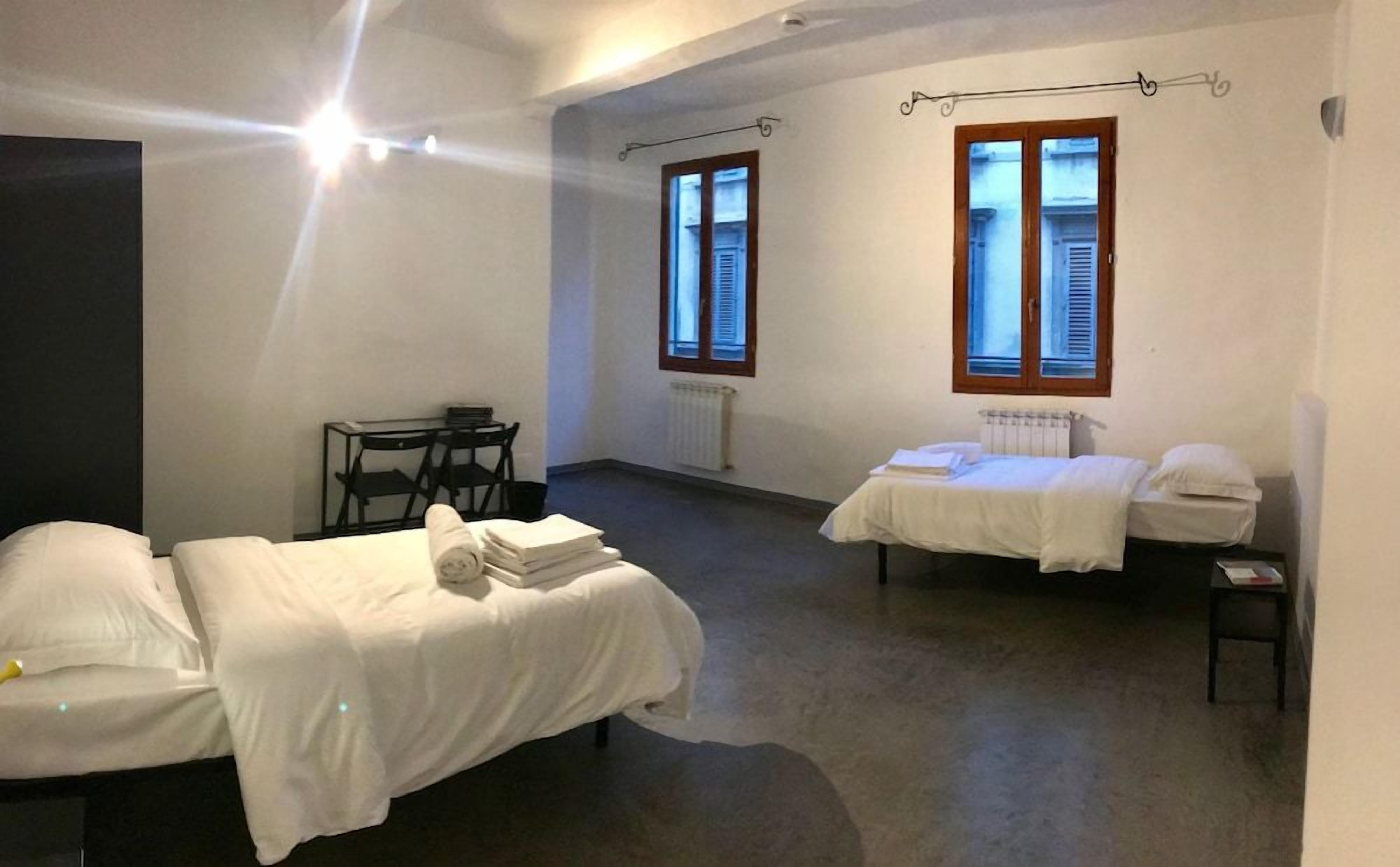 A room with two beds, a table, and a chair.