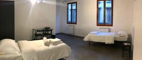 Una habitación con dos camas, una mesa y una silla.