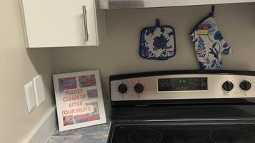 A kitchen with a stove, oven, and two wall-mounted ovens. There is a framed sign on the counter.