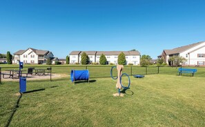 A grassy outdoor area with a blue exercise structure, a picnic table, and a bench.