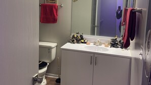 Un baño con inodoro, lavamanos, espejo y toallas rojas.