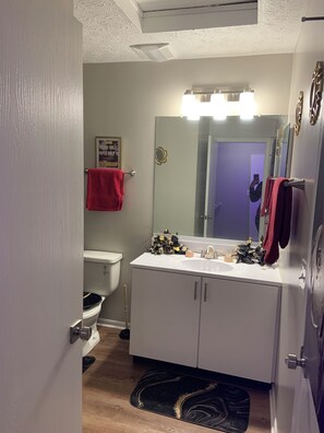 Een badkamer met toilet, wastafel, spiegel en rode handdoeken.