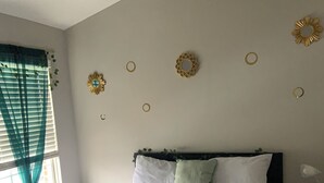 Un dormitorio con cama, mesita de noche, lámpara de pared y decoración en la pared.