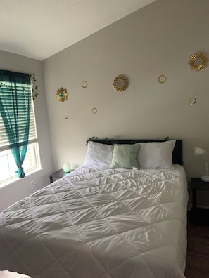 Een slaapkamer met een bed, een nachtkastje, een wandlamp en decoratieve wandkunst.