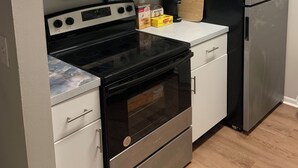 Una cocina moderna con armarios blancos, estufa negra, electrodomésticos de acero inoxidable y encimera de madera.