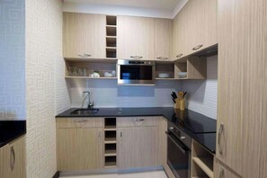 Une cuisine compacte avec des meubles en bois, un four encastré et un plan de travail noir.