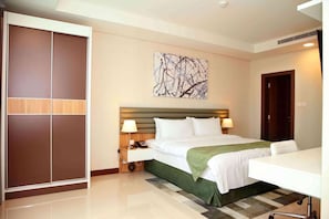 A hotel room with a bed, bedside tables, a desk, a chair, a wardrobe, and a painting on the wall. - Gulf Executive Residence Juffair Gerj (Manama)