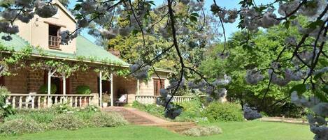 A house with a green roof, a porch, and a well-maintained lawn.