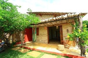 Una casa de ladrillo con una pérgola de madera, una puerta roja y un pequeño porche.
