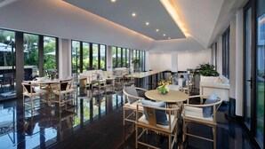 A spacious indoor area with multiple seating arrangements, large windows, and a polished floor. - Ramada Encore by Wyndham Jiusuo Downtown (Ledong)