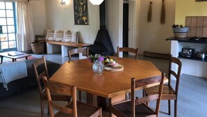 A dining area with a wooden table, chairs, a vase with flowers, and a hanging light fixture. - Tegwaan Country Getaway (Emgwenya)