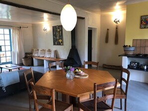 A dining area with a wooden table, chairs, a vase with flowers, and a hanging light fixture. - Tegwaan Country Getaway (Emgwenya)