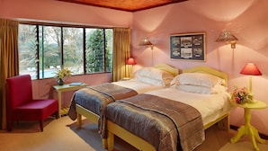 Una habitación de hotel con una cama, una silla, una mesita y un ventanal con cortinas.