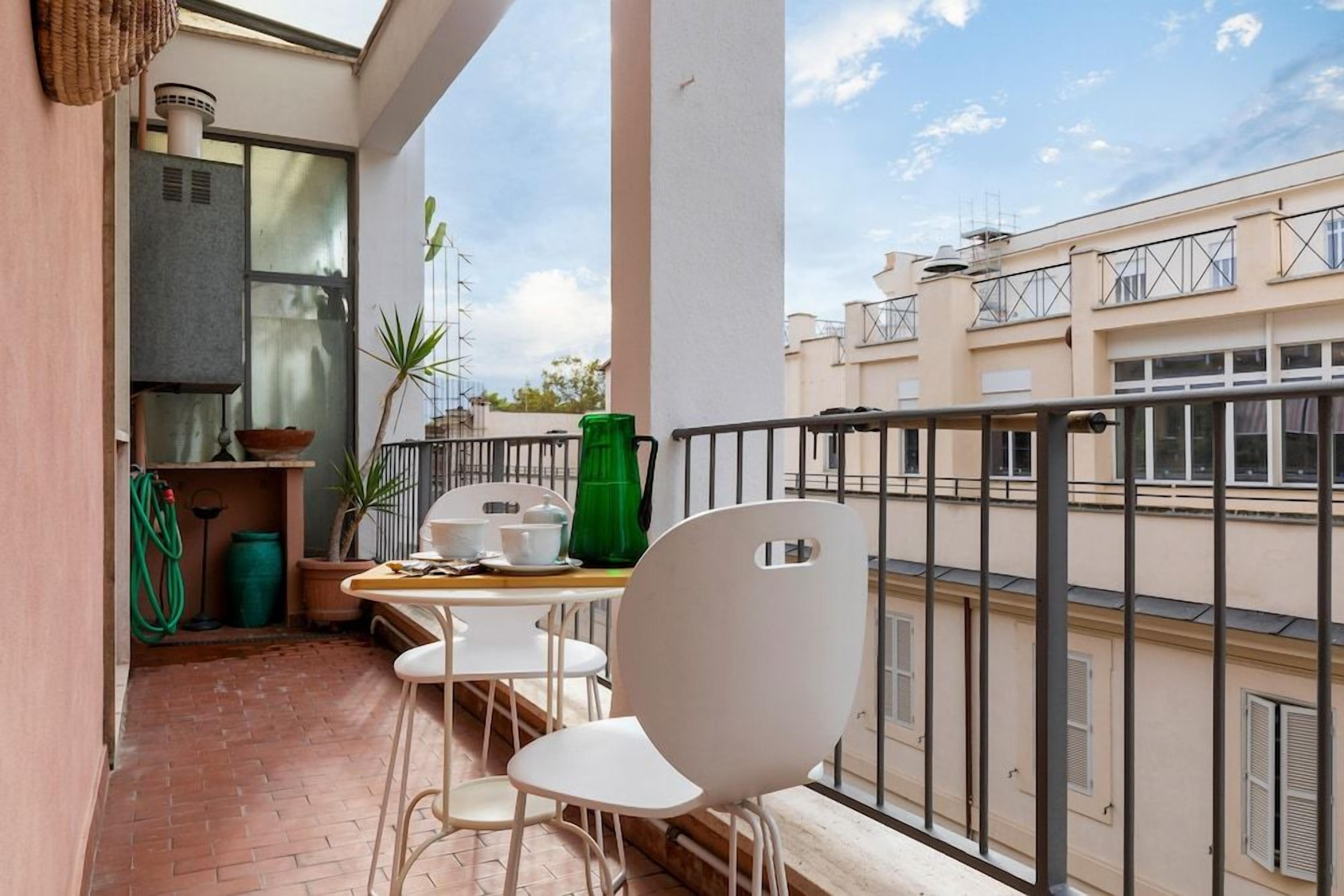 Un balcone con un tavolo, sedie, un vaso verde e una pianta in vaso.