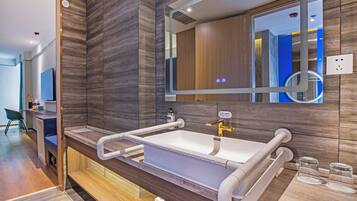 A modern bathroom with a large mirror, a white sink, and a wooden vanity.
