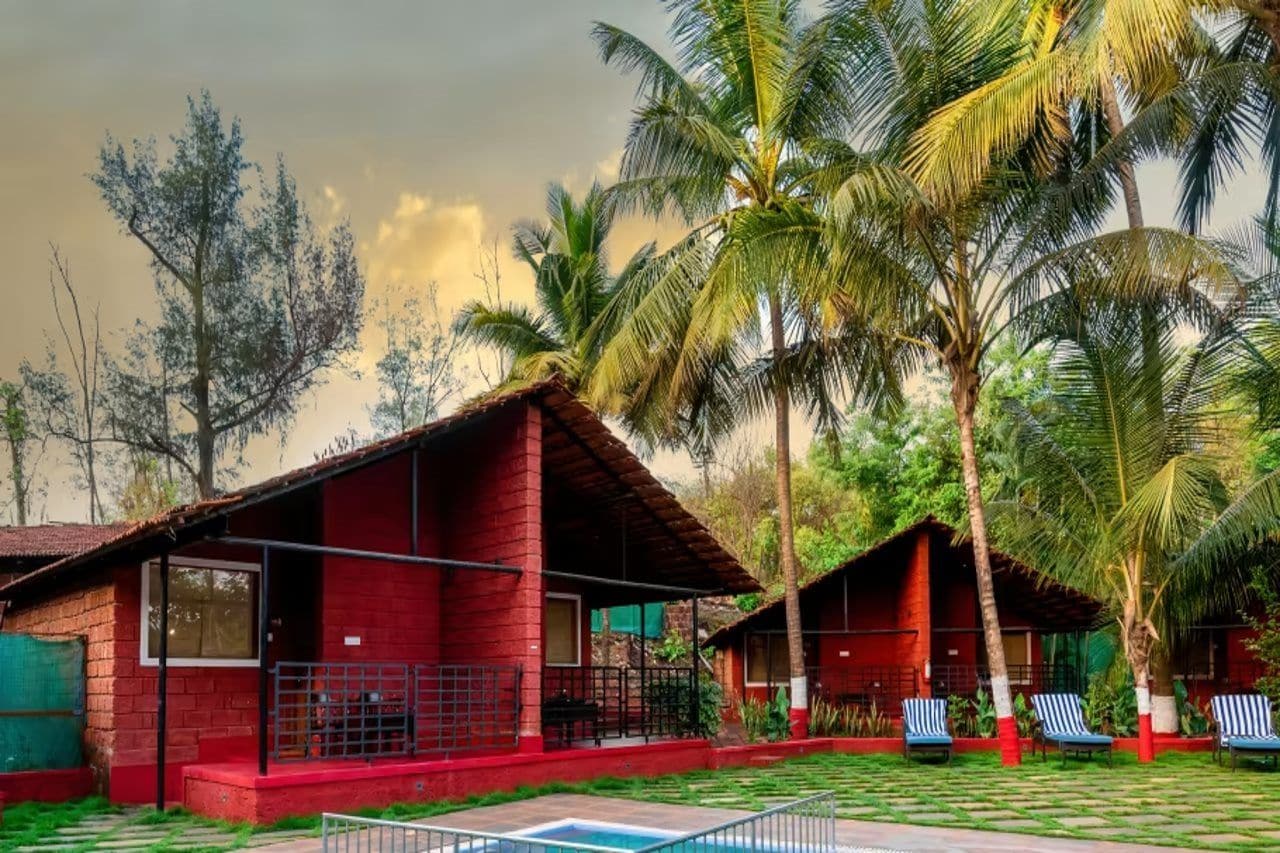 A red-roofed building with a pool and lounge chairs.