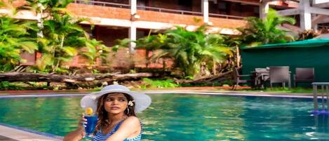 A person relaxing by a pool with a building in the background.