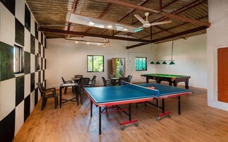 Um quarto com mesa de pingue-pongue, cadeiras, mesa de bilhar e mesa de xadrez.