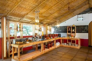 Cozinha rústica com bancadas de madeira, cardápio em lousa e diversos utensílios de cozinha.