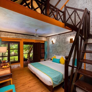 Un dormitorio con cama, escritorio, silla, escalera y vistas al exterior.