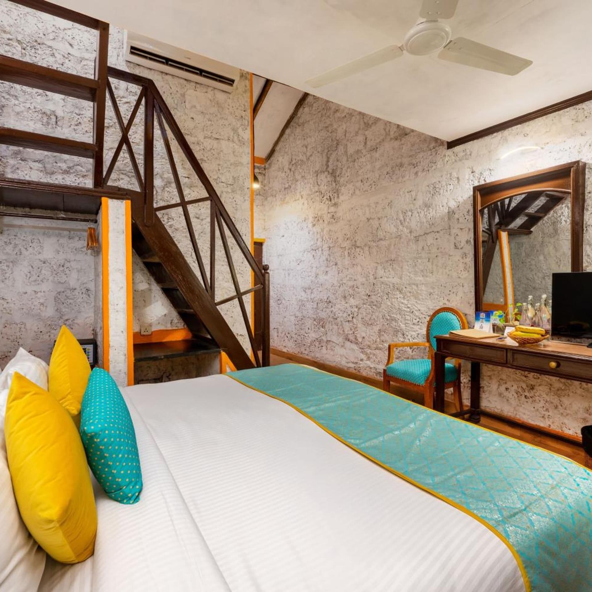Un dormitorio con una cama, un escritorio, una silla, un espejo y una escalera.