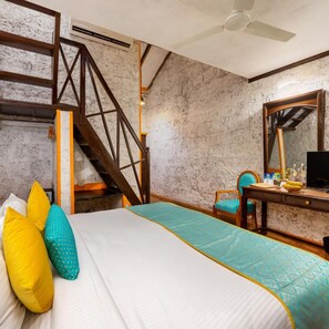 Ein Schlafzimmer mit einem Bett, einem Schreibtisch, einem Stuhl, einem Spiegel und einer Treppe.