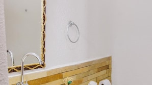 Ein Badezimmer mit einem weißen Waschbecken, einem Spiegel, einer Toilette und einem Handtuch an der Wand.