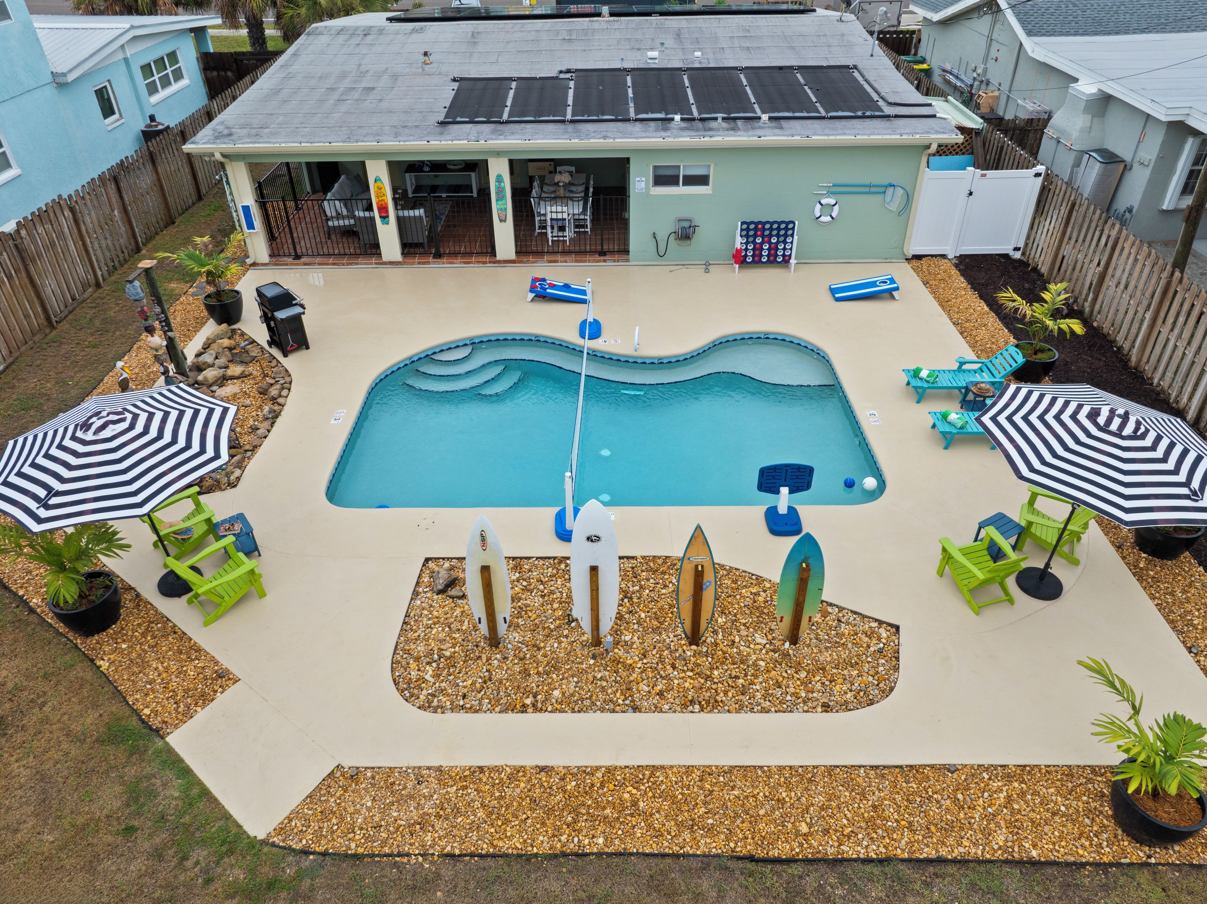A backyard with a swimming pool, lounge chairs, and umbrellas.