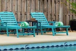 A poolside area with two turquoise lounge chairs, a small table, and a green towel. - NEW! Heated Pool·Retro Bungalow·Game Room·Walk to Beach (Cocoa Beach)