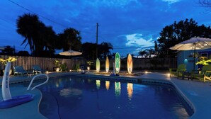 Una piscina con lettini e torce tiki.