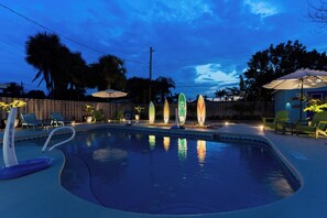A swimming pool with lounge chairs and tiki torches. - NEW! Retro Bungalow·Pool·Game Room·Walk to Beach (Cocoa Beach)