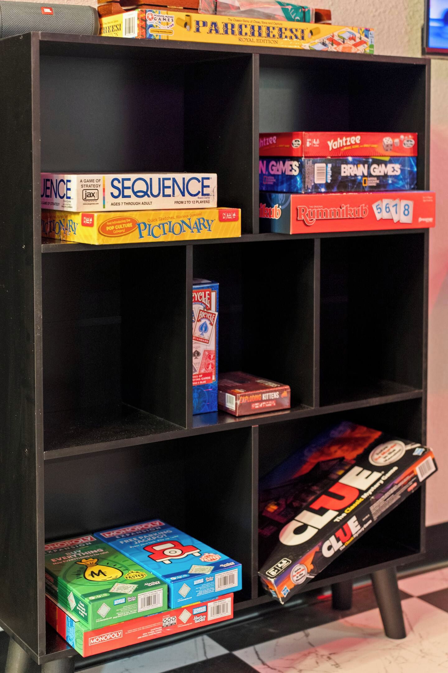 A bookshelf with various board games including Monopoly, Sequence, and Pictionary.